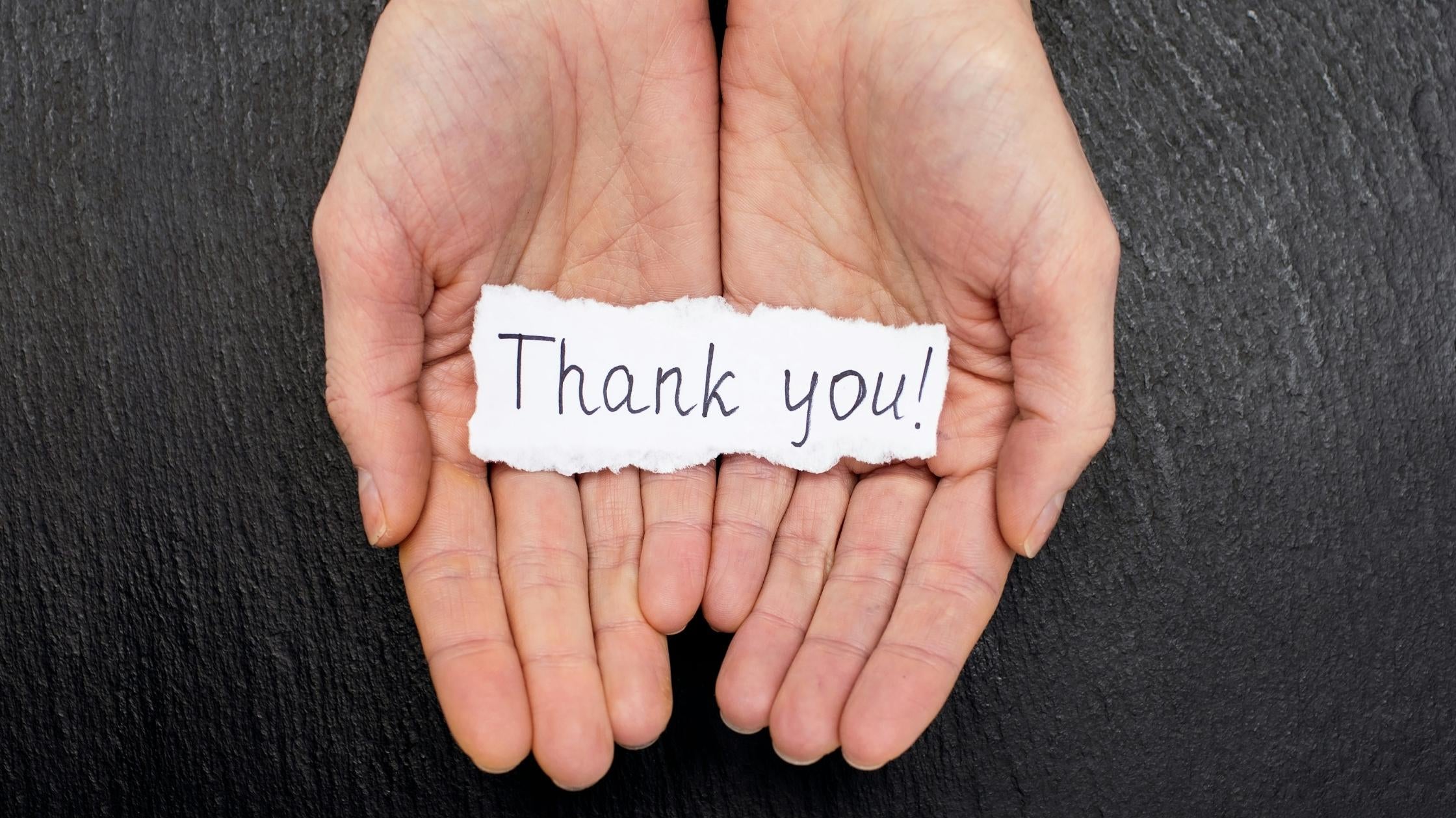 Geöffnete Hände halten ein Zettelchen mit Thank You – kreative Ideen, um Danke zu sagen und Wertschätzung zu zeigen