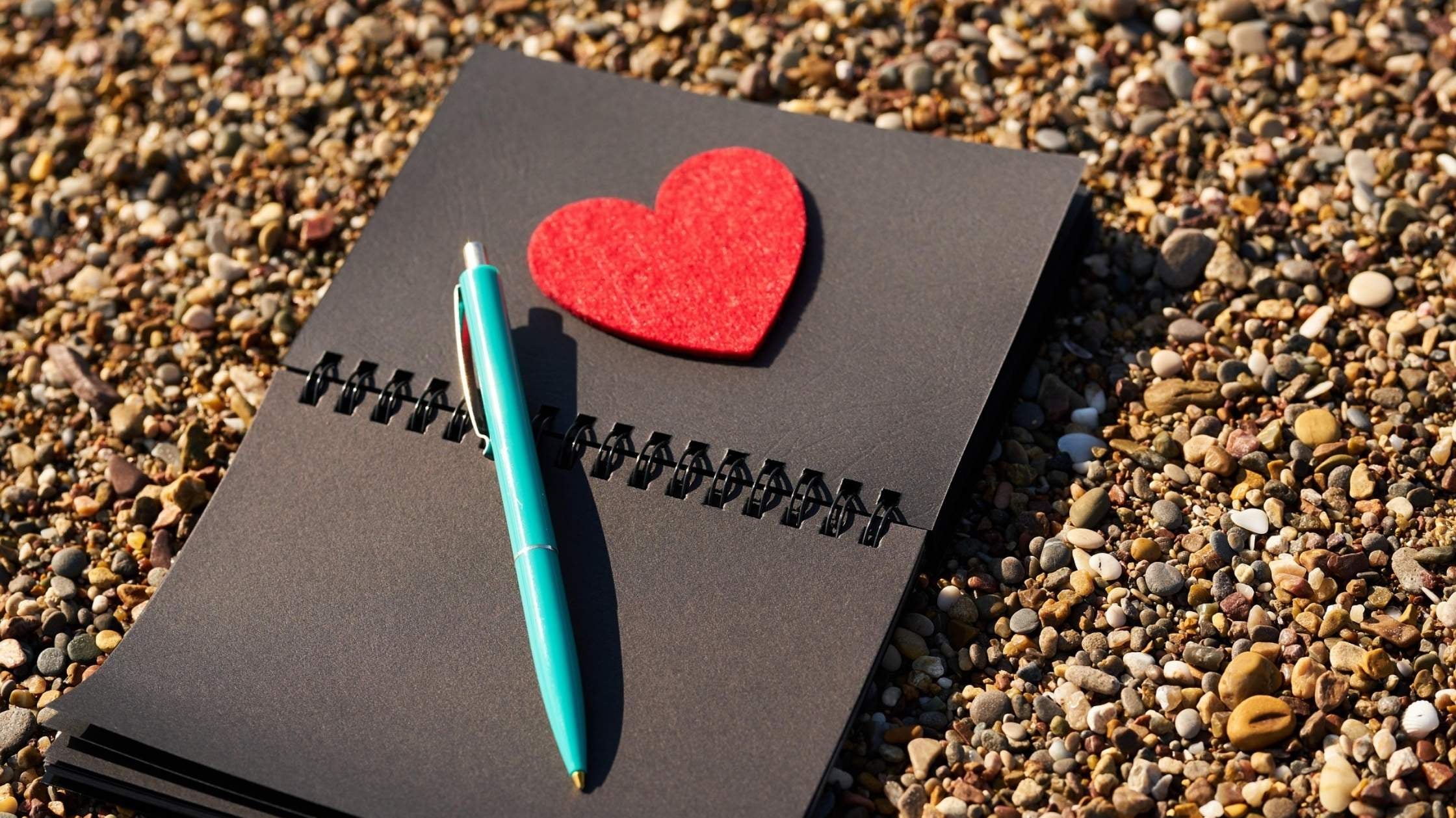 Notizbuch mit Herz und Stift auf Kieselstrand – Ideen für kleine Liebesbeweise im Alltag, die ans Herz gehen