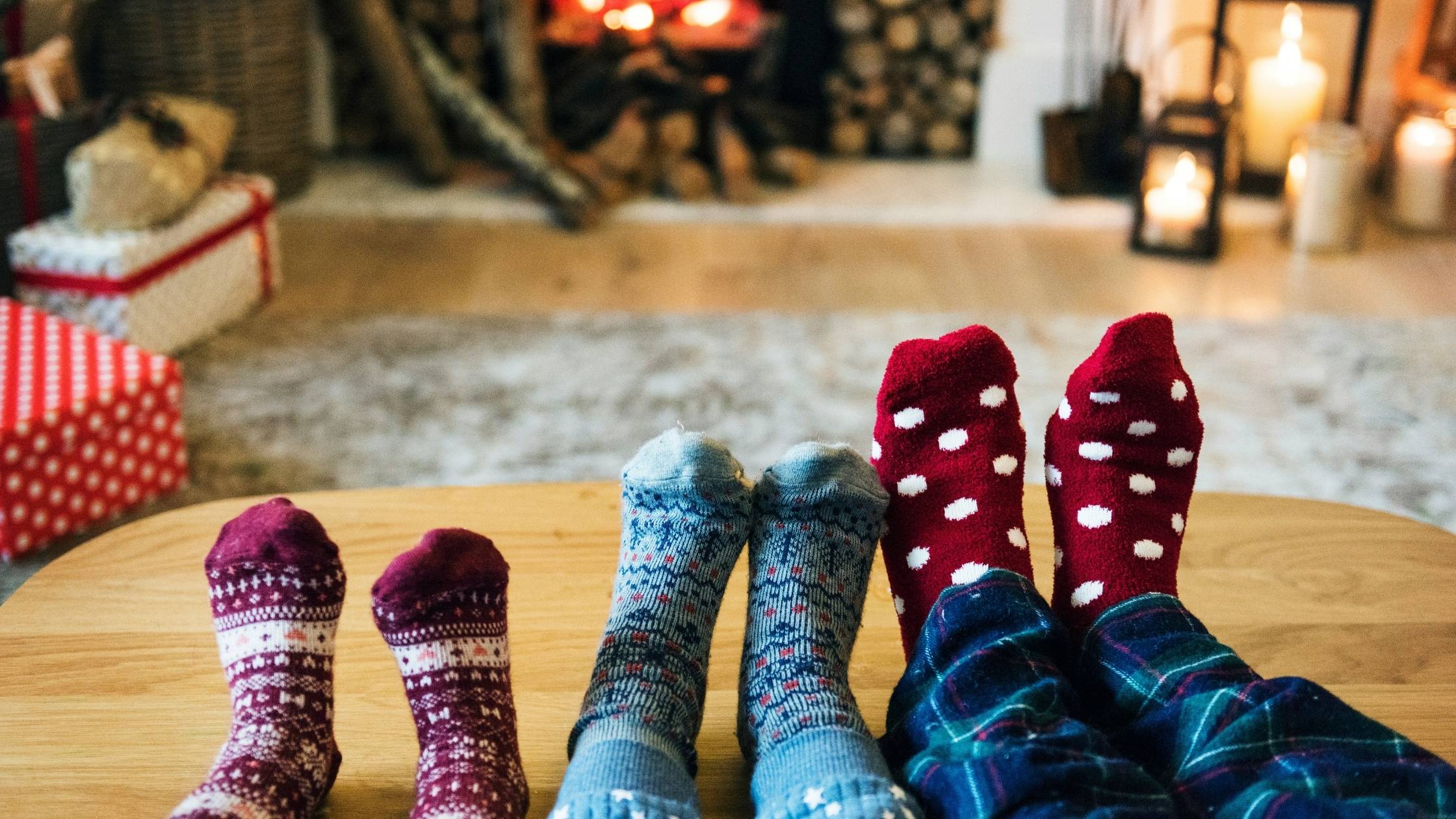 Drei Generationen mit hochgelegten Füßen im weihnachtlichen Wohnzimmer – gemütliche Familienzeit und Geschenke mit Humor